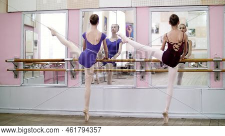 In Dancing Hall, Young Ballerinas In Purple Leotards Perform Developpe Aside On Pointe Shoes, Raise 