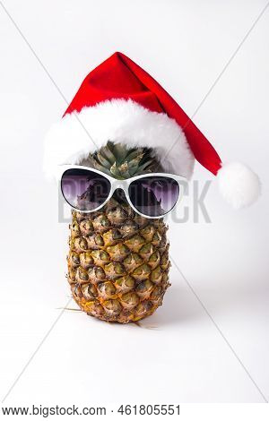 Pineapple In A Santa Claus Hat And Sunglasses. New Year's Holiday