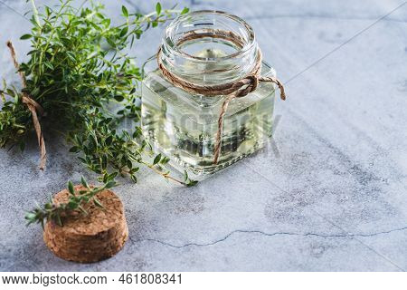 Thyme Oil In A Bottle, Thymus Green Leaves On Gray Background