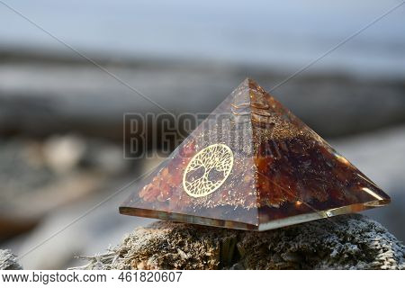 A Close Up Image Of An Carnelian Orgonite Energy Generating Pyramid With The Tree Of Life Symbol.