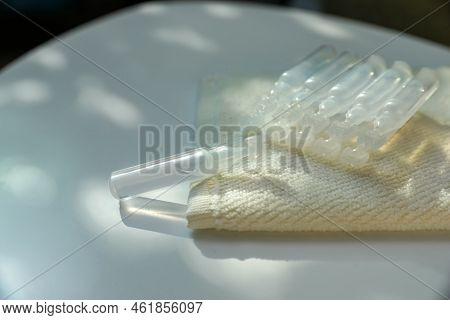 Single Dose Ampoules Of Sterile Isotonic Sea Water Solution And Towel On White Table, Closeup