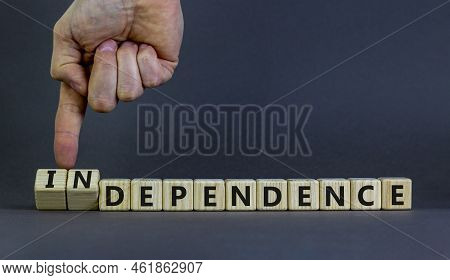 Dependence Or Independence Symbol. Businessman Turns Cubes And Changes The Word 'dependence' To 'ind