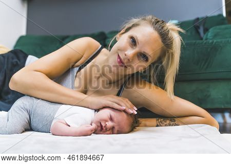 Caucasian Woman With Blond Hair Resting On Floor On Her Side Caressing Her Newborn Baby Boy Looking 