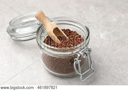 Glass Jar With Wooden Scoop And Buckwheat Tea Granules On Light Grey Table