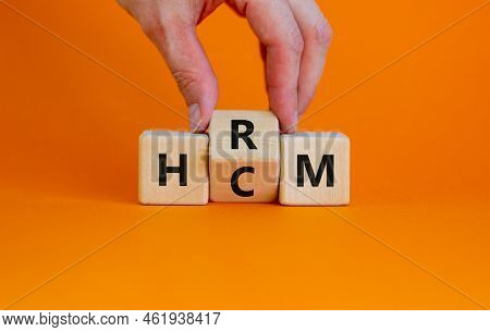 Human Resource And Capital Management Symbol. Businessman Turns Cubes, Changes The Word Hcm To Hrm. 