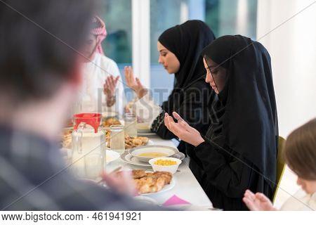 Muslim family making iftar dua to break fasting during Ramadan.