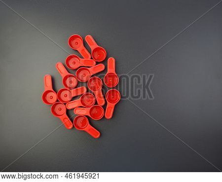 Red Measuring Spoons For Sports Nutrition On A Gray Background. A Bunch Of Plastic Measuring Spoons