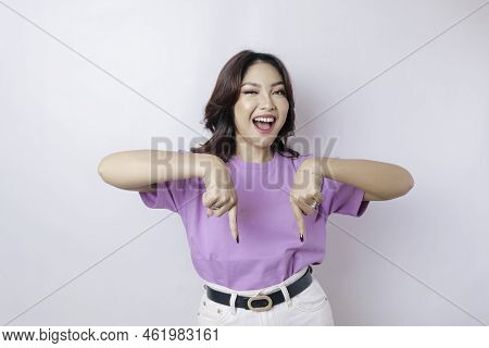 Excited Asian Woman Wearing Lilac Purple T-shirt Pointing At The Copy Space Downside Her, Isolated B