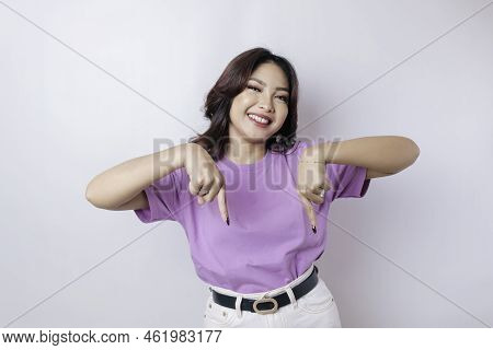 Excited Asian Woman Wearing Lilac Purple T-shirt Pointing At The Copy Space Downside Her, Isolated B