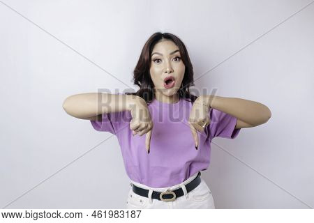Shocked Asian Woman Wearing Lilac Purple T-shirt Pointing At The Copy Space Downside Her, Isolated B