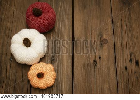 Three Pumpkins Crocheted Stand On A Wooden Table. View From Above. Orange. White And Red Yarn Tyva, 