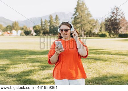 Close Up Portrait Of A Lovely Happy Young Woman In Sunglasses Listening To Music Through Wireless Ea