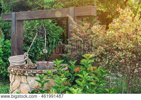 Beautiful Artesian Well Made By Stones And Wheel Pulley With Metal Bucket And Rope In Peaceful Garde
