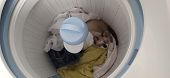 A beige and white kitten laying inside of a washing machine.
