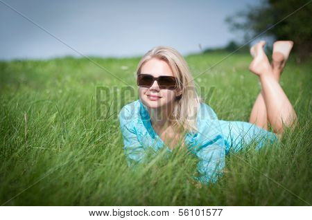 Pretty blonde girl relaxing outdoor in green grass