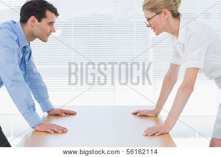 Side view of smiling young business couple looking at each other with palms at the office desk