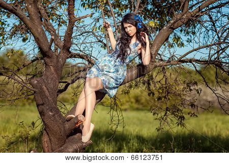 Beautiful Brunette Girl Sitting On A Tree.