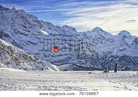 Red Helicopter Flying Over Swiss Ski Resort Near Jungfrau Mountain
