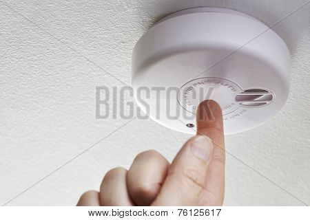 Close Up Of Hand Testing Domestic Smoke Alarm