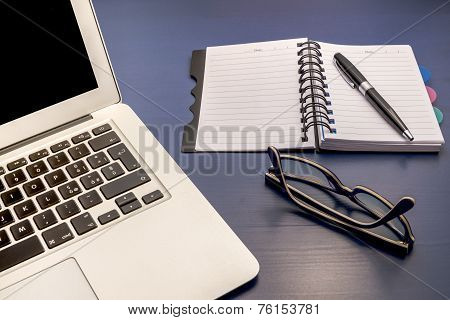 Office desk with laptop and glasses