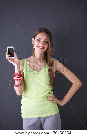 Beautiful young woman holdiing cellphone, isolated on grey