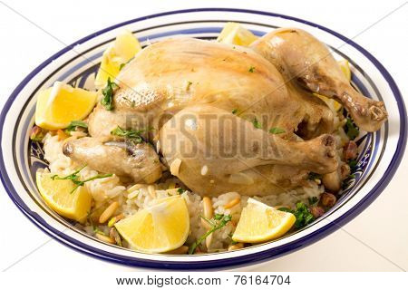 Chicken pilaf, or riz bi djaaj, traditional Arab and Mediterranean boiled chicken and rice dish, served with roasted nuts and lemon wedges.