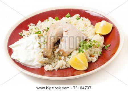 Chicken pilaf, or riz bi djaaj, traditional Arab and Mediterranean boiled chicken and rice dish, served with roasted nuts and lemon wedges.