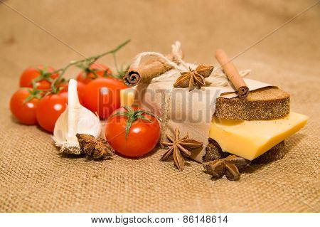 Sandwich With Cheese Wrapped In Paper,cinnamon Stick, Cherry Tomatoes And Garlic On Old Cloth