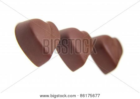 three chocolate candy in the shape of heart on white background