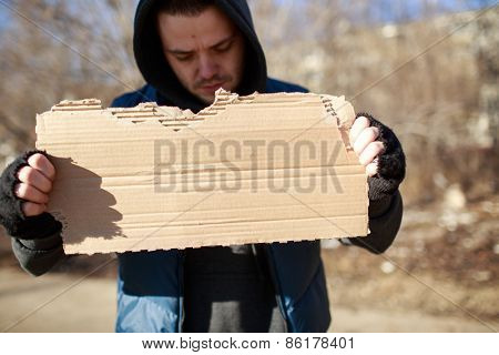 Homeless man holds blank cardboard for your text