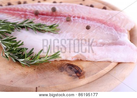 Pangasius fillet on wooden cutting board on white background