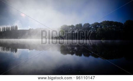 Trees Reflecting On Water Surface On Lake Karapiro In New Zealand. Misty Scenery