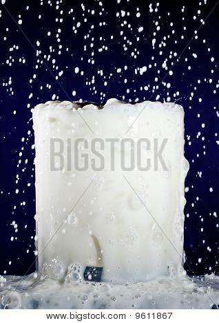 Überfülltes Glas Milch mit plantschen Tropfen auf tiefes Blau