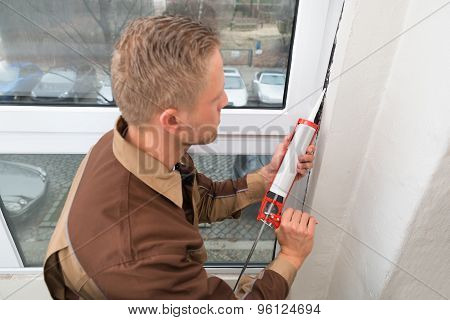 Man In Overall Applying Silicone Sealant