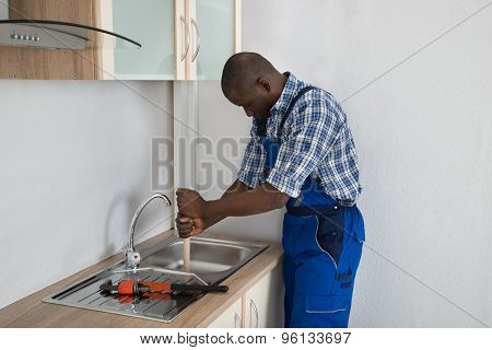 Plumber Pressing Plunger In Sink