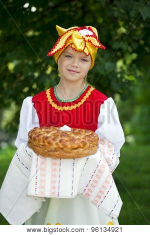 Little girl is dressed in the Russian national dress. She holds in his hands the fresh loaf. It is a custom to meet the guests.