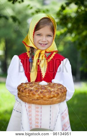 Little girl is dressed in the Russian national dress. She holds in his hands the fresh loaf. It is a custom to meet the guests.