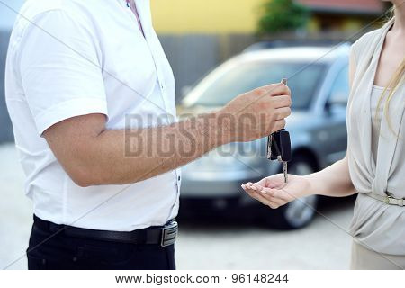 Car salesman give new car keys to customer
