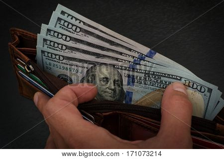 Salary of several hundreds american dollars shown in brown leather wallet