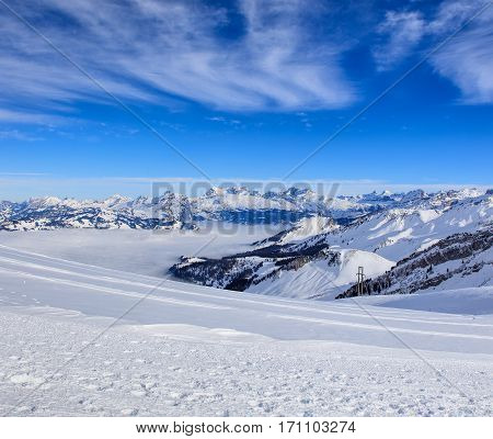 Wintertime view from Fronalpstock mountain in the Swiss Canton of Schwyz, summits of the Swiss Alps rising from sea of fog in the background.