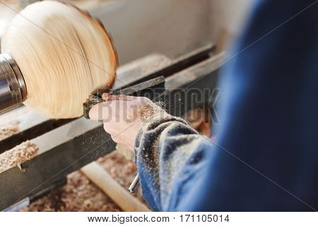 Man's hands in  blue jeans suit working with woodcarving machine and wood, shavings on table, close up, copy space.