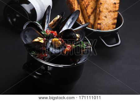 Casserole With Mussels. A Bottle Of Wine And A Baguette, Black Background.