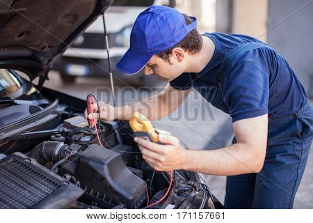 Car electrician troubleshooting a car engine