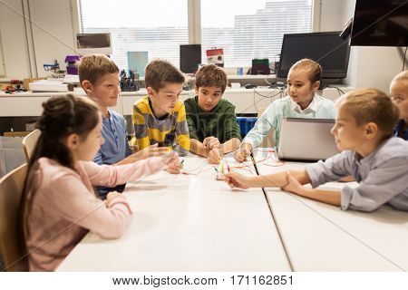 education, children, technology, science and people concept - group of happy kids with laptop computer playing and invention kit at robotics school lesson