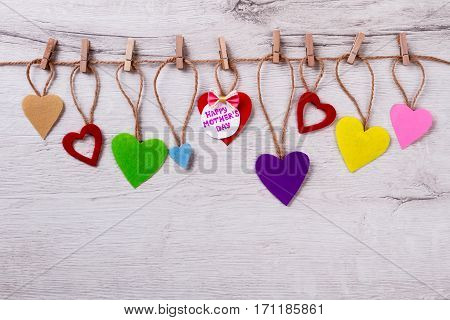 Mother's Day card on rope. Heart, bow tie, greeting paper. Be original when congratulating. Beautiful holiday for priceless person.