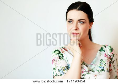 Young beautiful female thinking and pondering over something with her finger on the chin looking aside isolated on white background