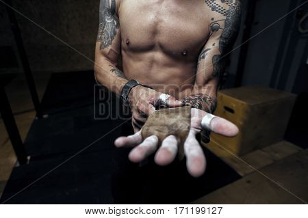 Cropped shot male athlete wearing gymnastics grips for doing pull up workout.