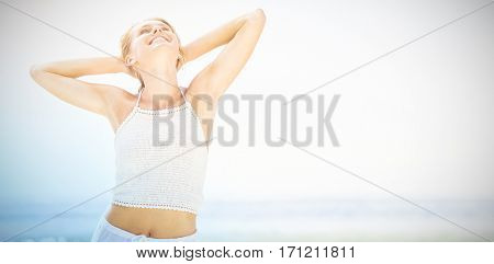Happy young woman with hands behind head against sky
