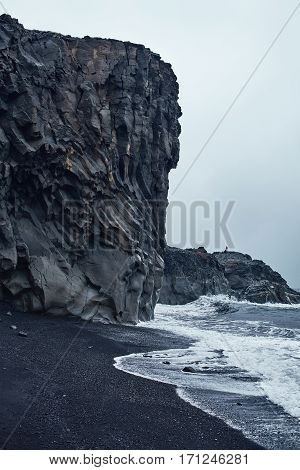 black beach in Iceland. Bank of the Ocean with black sand and cliffs