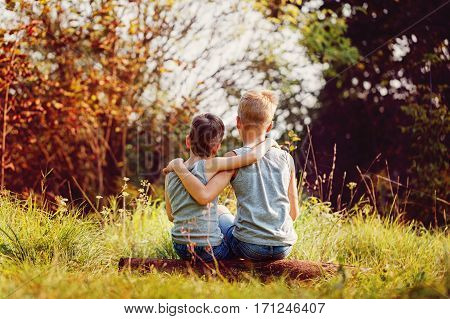 Two little boys friends hug each other in summer sunny day. Brother love. Concept friendship. Back view.